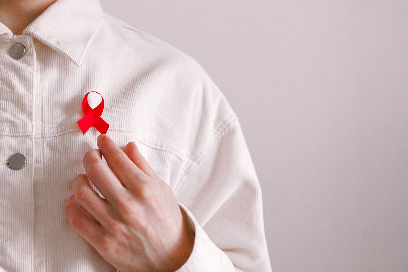 Vīrietis ar sarkanu lentīti uz krekla Pasaules AIDS dienā