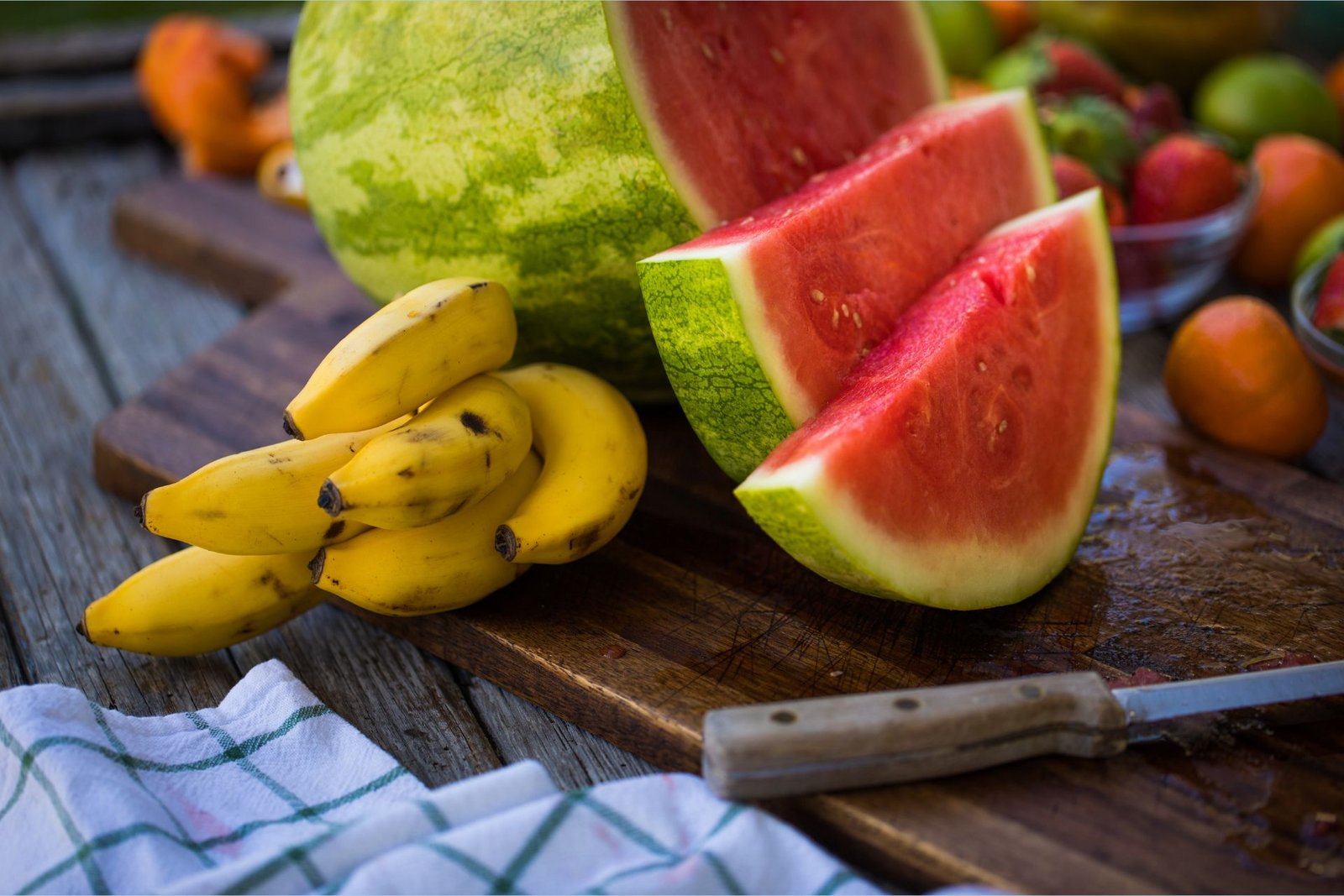 Ar kāliju bagāti banāni atrodas blakus ar L-citrulīnu bagātam šķēlītēm sagrieztam arbūzam uz šķēlēšanas dēlīša.